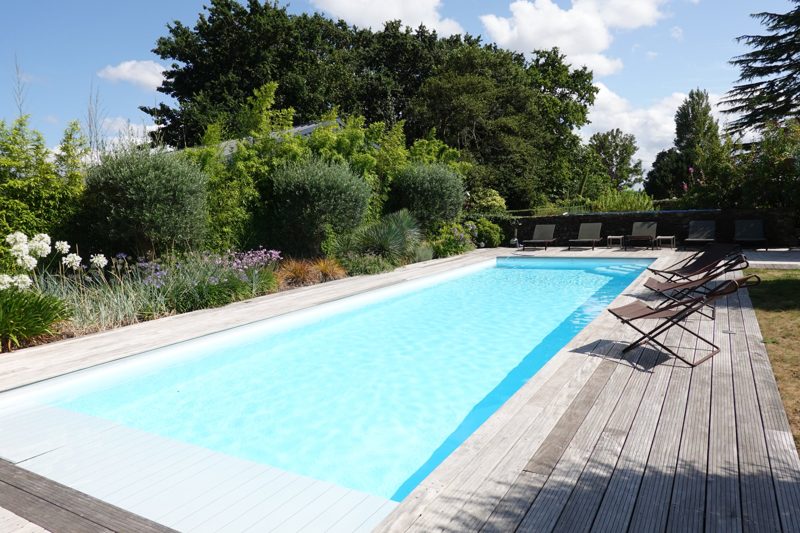 La piscine, entre deck de bois et massifs fleuris